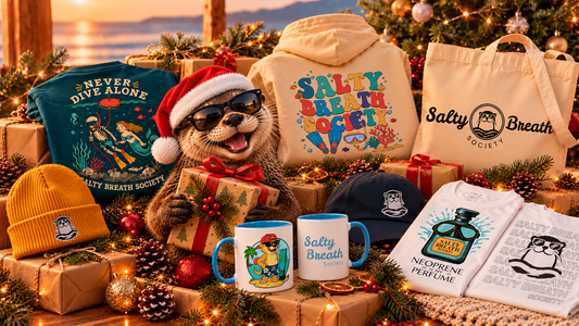 Idées cadeaux pour apnéiste et plongeur : t-shirts, hoodie, bonnet, casquette, mugs et tote bag Salty Breath Society autour d’une loutre en bonnet de Père Noël