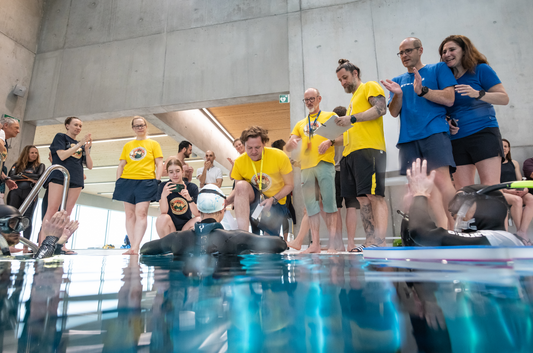 Juges en t-shirts jaunes SBS et staff au bord du bassin lors des Championnats suisses d'apnée indoor à Romont, pendant la sortie d'un athlète